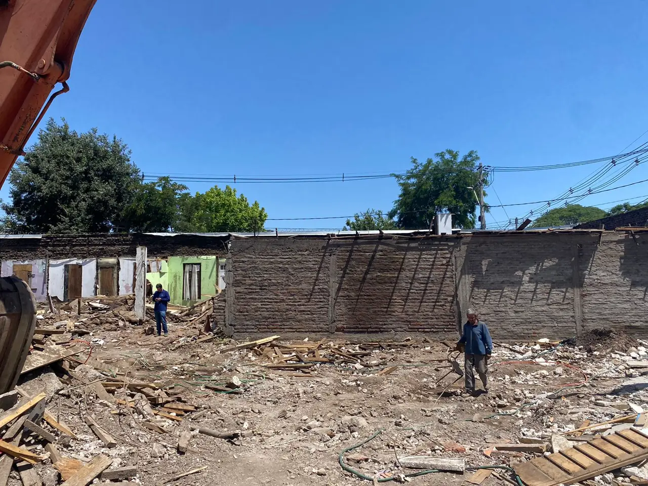 Terreno casi despejado tras una demolición, con muro medianero conservado y trabajadores en faena