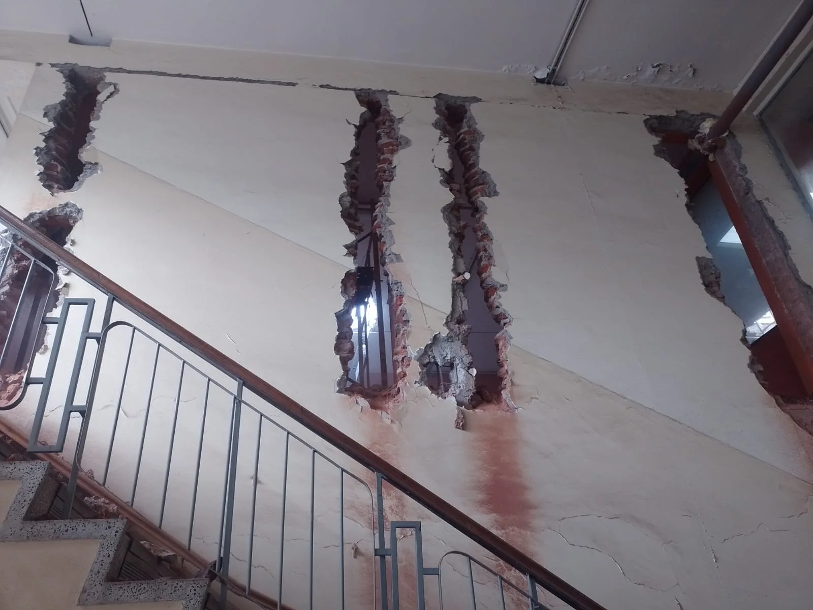 Demolición parcial de muro interior junto a una escalera, con cortes en la albañilería