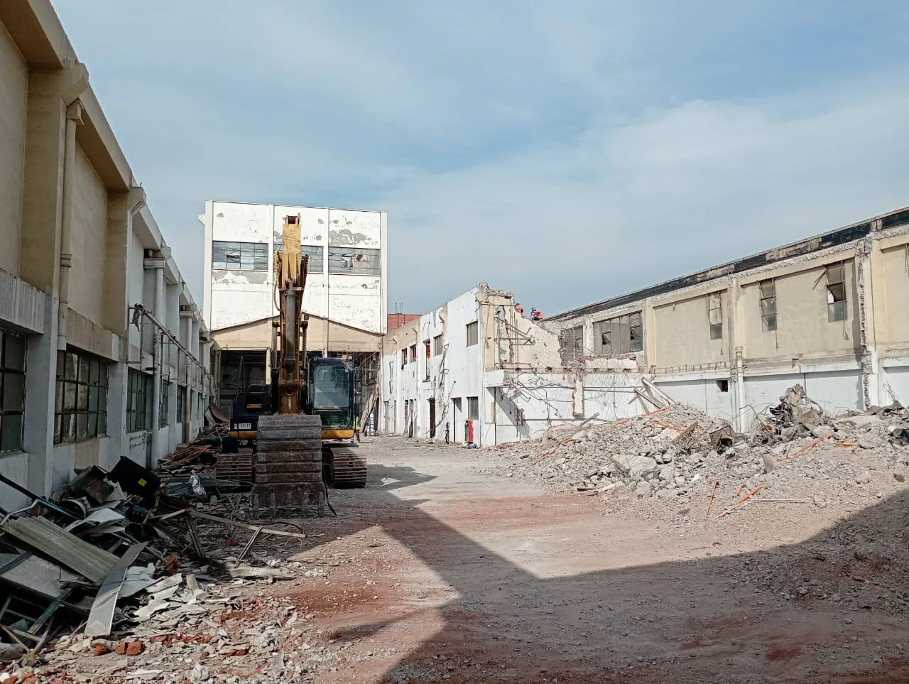 Excavadora trabajando en la demolición de un recinto industrial con escombros de hormigón